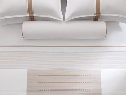 A close up overhead shot of a bed made with beige center stripe covers and pillow cases.