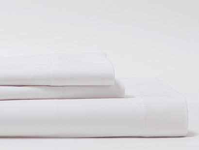 A white folded sheet with two white folded pillowcases stacked on top.